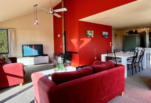 a living room with red walls and a red couch at Pukeko Palace - Lake Tekapo in Lake Tekapo