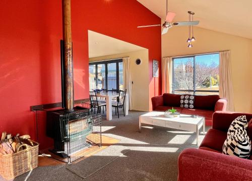 a living room with red walls and a fireplace at Pukeko Palace - Lake Tekapo in Lake Tekapo