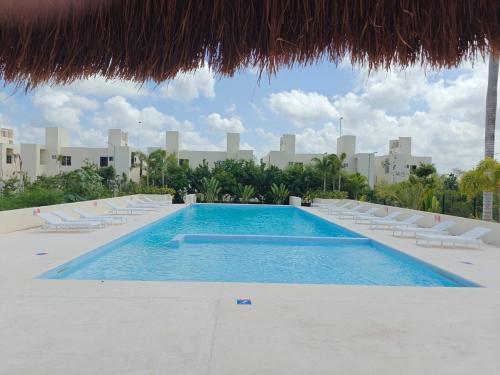 a swimming pool with lounge chairs and a straw umbrella at Casa Maya comfortable apartment in Tulum in Tulum