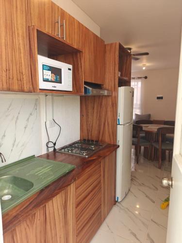 a kitchen with wooden cabinets and a white refrigerator at Casa Maya comfortable apartment in Tulum in Tulum