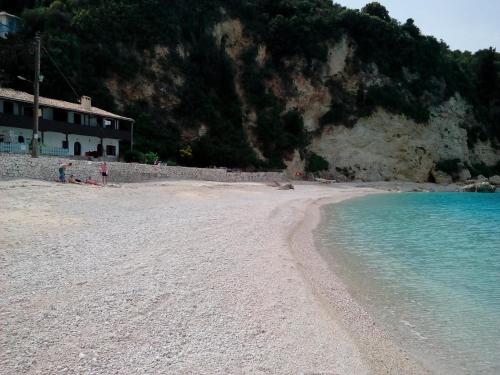 una spiaggia con acqua blu e un edificio sopra di Fetsis Apartments a Ayios Nikitas