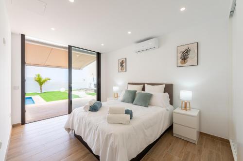 a white bedroom with a large bed with a chair at Saras Village in Adeje