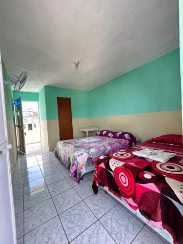 two beds in a room with blue and green walls at Hospedaje El Paraíso in San Pedro La Laguna