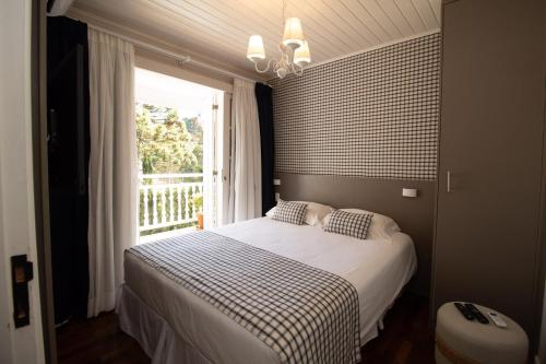 a bedroom with a white bed with a window at Secreto Boutique Hotel in Campos do Jordão