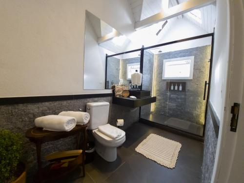 a bathroom with a toilet and a glass shower at Secreto Boutique Hotel in Campos do Jordão