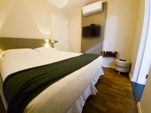 a bedroom with a large bed and a tv at Secreto Boutique Hotel in Campos do Jordão
