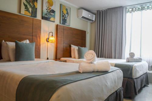 a hotel room with two beds with towels on them at Majestic City Suites & Beach Hotel in Willemstad