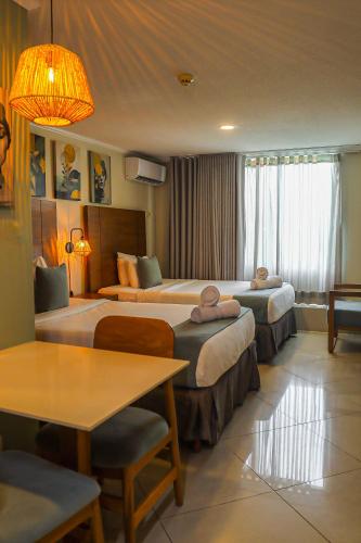 a hotel room with two beds and a table at Majestic City Suites & Beach Hotel in Willemstad