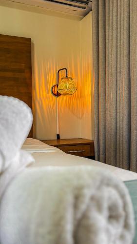 a bedroom with a bed and a lamp next to a curtain at Majestic City Suites & Beach Hotel in Willemstad