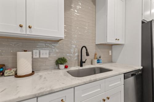 a white kitchen with a sink and a refrigerator at Voodoo House KING Bed Garage Fast WiFi 65 Tv in Lafayette