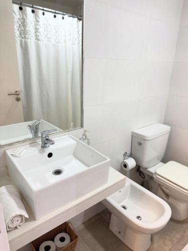 a white bathroom with a sink and a toilet at Alem Apartamento in La Porteña