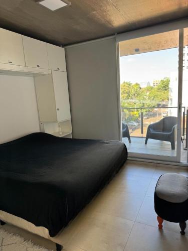 a bedroom with a black bed and a balcony at Alem Apartamento in La Porteña