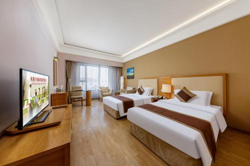 a hotel room with two beds and a flat screen tv at Weihai Haiyue Jianguo Hotel in Weihai