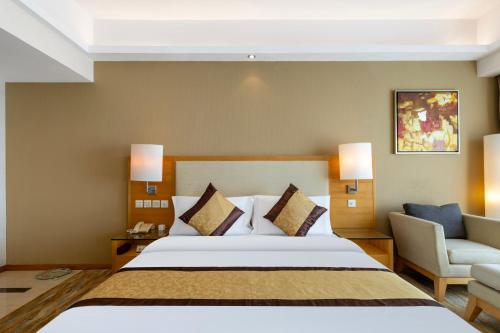 a hotel room with a bed and a chair at Weihai Haiyue Jianguo Hotel in Weihai