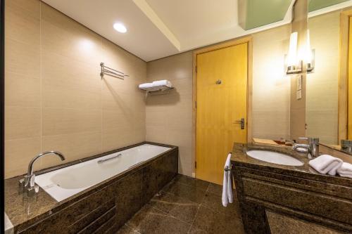 a bathroom with a tub and a sink at Weihai Haiyue Jianguo Hotel in Weihai