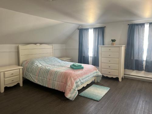 a bedroom with a bed and two dressers and windows at Large room in private home in Rimouski