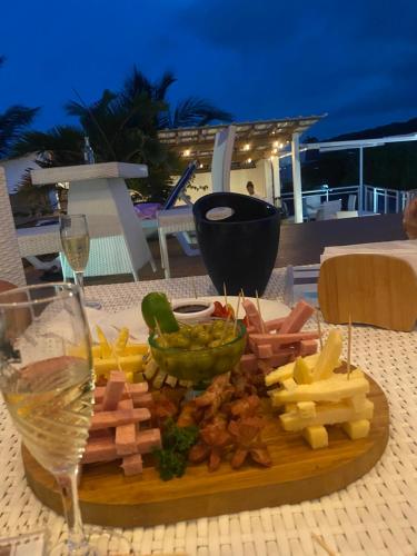 a plate of cheese and vegetables on a table with a glass of wine at Hotel Down Town Cabrera in Cabrera