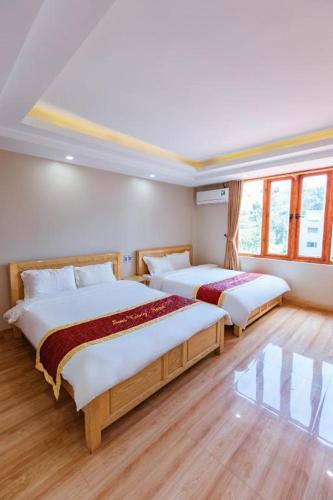 two beds in a room with wooden floors and windows at SAPA HUB hostel in Sa Pa