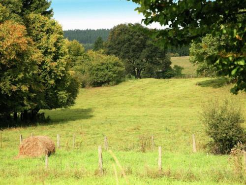 a field with a haystack in a field with trees at Luxurious Farmhouse in Falaen with Sauna in Maredsous
