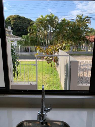 a bathroom window with a sink and a view of a yard at kitnet dos Sonhos in Florianópolis