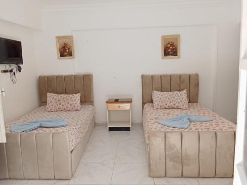 - 2 lits dans une petite chambre avec une table de nuit dans l'établissement R1 CH21 studio 2 beds poolside garden terrace Green Beach, à El Alamein