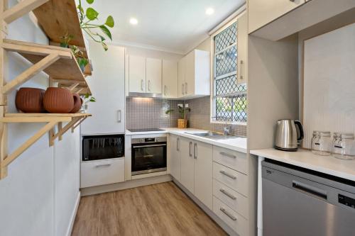 Una cocina con gabinetes blancos y una ventana. en Bay Breeze, en Deception Bay