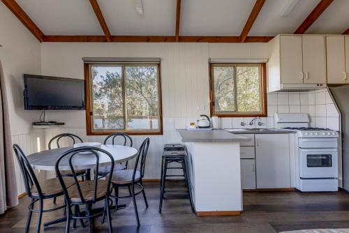 a kitchen with a table and chairs and a kitchen with a stove at Ocean Grove Holiday Park in Ocean Grove