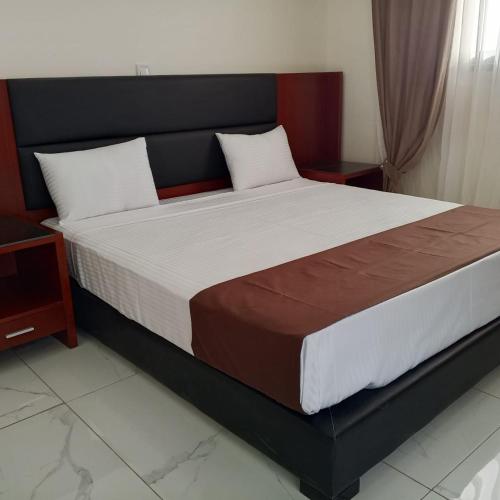 a large bed in a bedroom with two night stands at Melias Hotel Diamniadio in Dogar