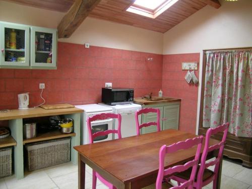 a kitchen with a table and pink chairs and a stove at Gîte familial avec pêche, cascade, animaux et activités variées, proche de Vichy et Le PAL - FR-1-489-122 in Barrais-Bussolles