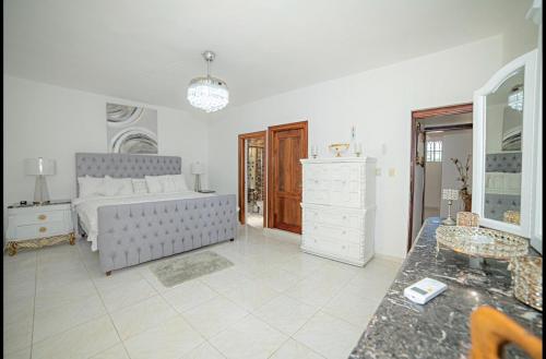 a white bedroom with a bed and a table at Spacious and secure villa in Puerto Plata