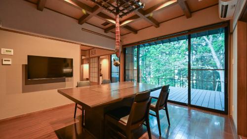 a dining room with a table and chairs and a large window at Kaze no Tani no Iori in Gamagori