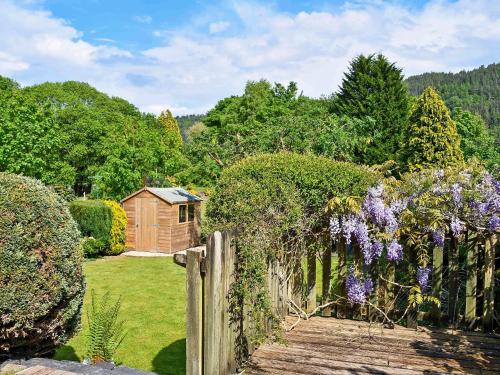 a garden with a fence and a wooden house at Rose Cottage in Betws-y-coed
