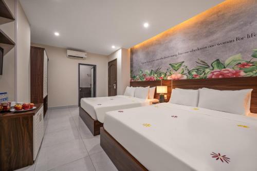 a bedroom with two beds and a painting on the wall at KLY Hotel Vung Tau in Vung Tau