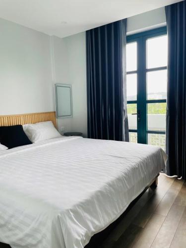a bedroom with a large white bed and a window at 118 Orchid in Phú Quốc