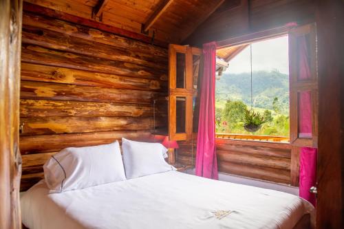 a bed in a wooden room with a window at Hospedaje Vista Hermosa Salento in Salento
