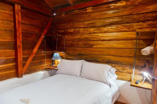 a bed in a room with wooden walls at Hospedaje Vista Hermosa Salento in Salento
