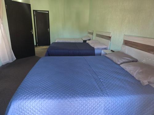 two beds in a room with blue sheets and pillows at Posada-Hotel El Remanso in Itá