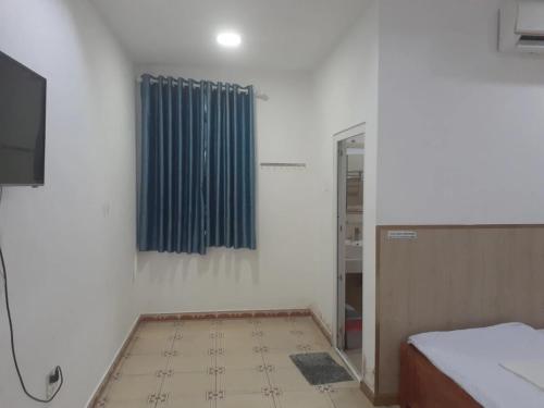 a room with a bed and a window with blue curtains at Hoàng Yến Hotel Mỹ Tho in My Tho