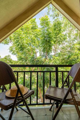 two chairs on a balcony with a view of trees at Ana-as Apartelle (GGL) in Panglao