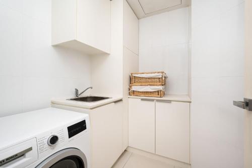 a white laundry room with a washer and dryer at Beachfront Hampton in Melbourne