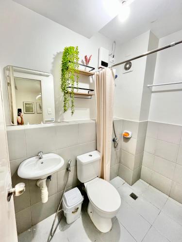 a white bathroom with a toilet and a sink at Cozy 2BR Stay for 6pax in High-Floor, Wi-Fi & Family Games near IT Park Cebu- Unit Scarlett by GERRA in Mandaue City
