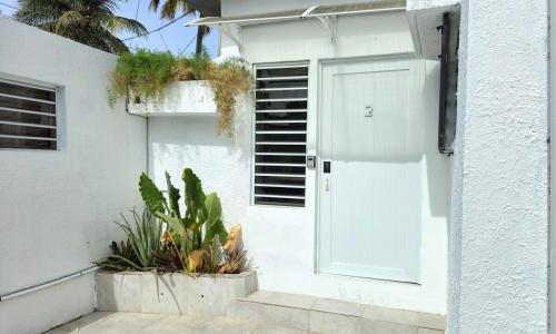 een wit huis met een witte deur en wat planten bij Oscar Building - Apto#2 in San Juan