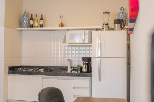 a kitchen with white cabinets and a white refrigerator at Loft Encantador com Ar Cond prox Centro in Itatiba