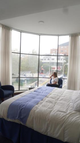 a woman sitting in a chair next to a bed at Delfines Apart Hotel in La Paz