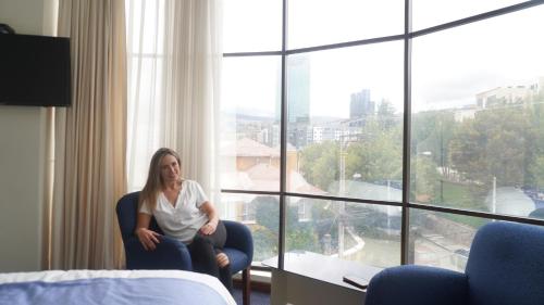 a woman sitting in a chair in front of a window at Delfines Apart Hotel in La Paz