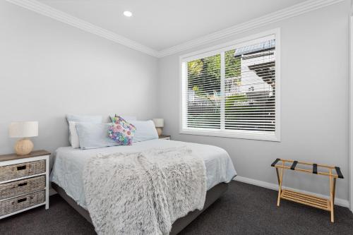 a white bedroom with a bed and a window at The Weiti Waterfront in Whangaparaoa