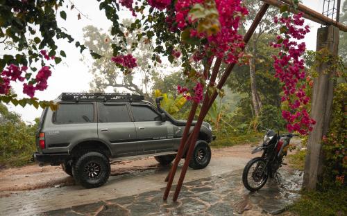a gray truck parked on a dirt road with a motorcycle at Minca Sintropia - Sustainable Lodge & Organic Coffee Finca in Minca