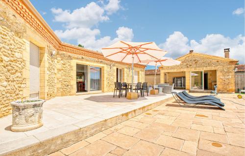 a patio with a table and an umbrella and chairs at Charmante Maison Avec Piscine in La Douze
