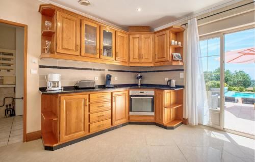 a kitchen with wooden cabinets and a large window at Charmante Maison Avec Piscine in La Douze