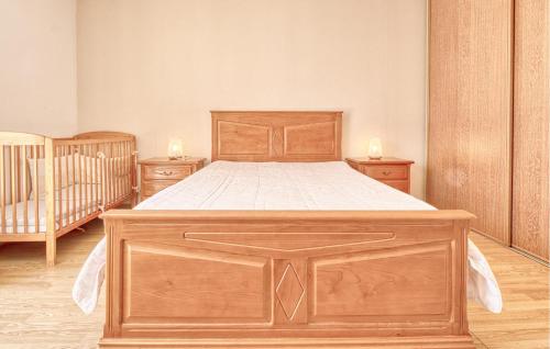 a large wooden bed in a bedroom with two cribs at Charmante Maison Avec Piscine in La Douze